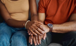 image from neck down of two adults holding hands