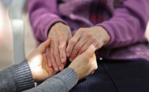 A youthful pair of hands holds an elderly pair of hands