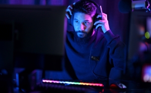 Man sitting at computer puts on gaming headset