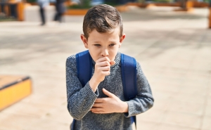 child coughing into hand outside school