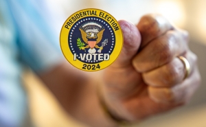 A man holds up a sticker that reads &quot;Presidential Election I Voted 2024&quot; on the first day of Virginia&#039;s in-person early voting at Long Bridge Park Aquatics and Fitness Center on September 20, 2024, in Arlington, Virginia.