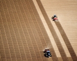 Aerial view of 2 tractors planting potatoes in the fertile farm fields of Idaho, during the spring.