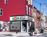 Man standing in front of typical corner shop in East Baltimore