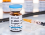 a vial labeled COVID-19 BA.4/BA.5 Bivalent Booster injection only, with a syringe next to it