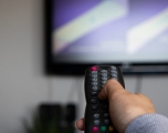 Person aiming remote control at television
