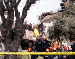Istanbul first responders standing on top of a wrecked house and rubble handing off a deceased person in a body bag to other first responders on the ground