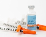 a vial of insulin with three syringes resting next to it