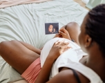 Black pregnant woman holding a sonogram
