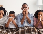 A family of four suffering from a respiratory illness blow their noses.