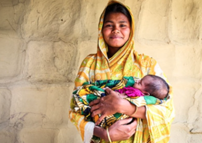 Woman wearing a sari is standing and holding her new infant