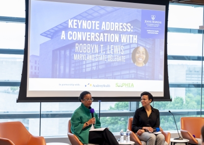 Two women, Department Chair Keshia Pollack Porter and Maryland State Delegate Robbyn T. Lewis, sit in front of a large screen that's entitled Keynote Address: A Conversation With Robbyn T. Lewis