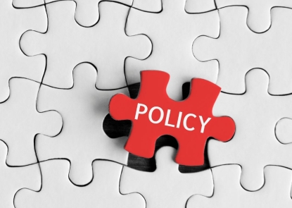 A red puzzle piece labeled policy is slotted into the last empty space of an otherwise complete, white puzzle piece grid.